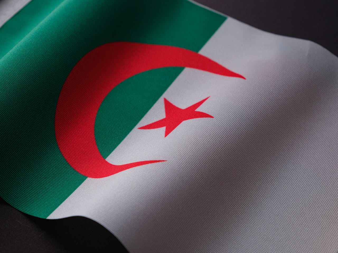 Closeup of the Algerian flag displaying its emblem on textured fabric.