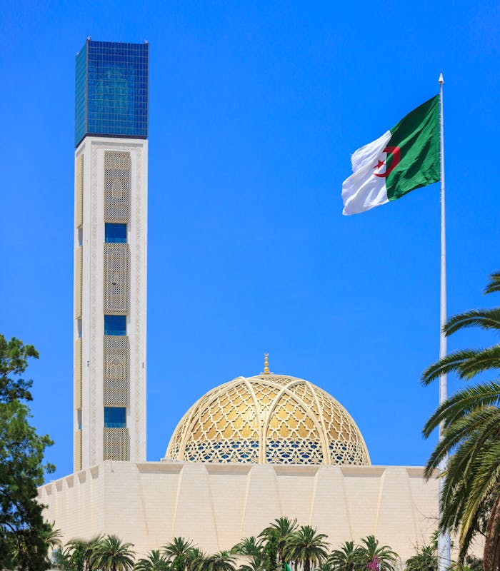 Capture of the Great Mosque of Algiers against a vibrant blue sky, featuring its dome and minaret.